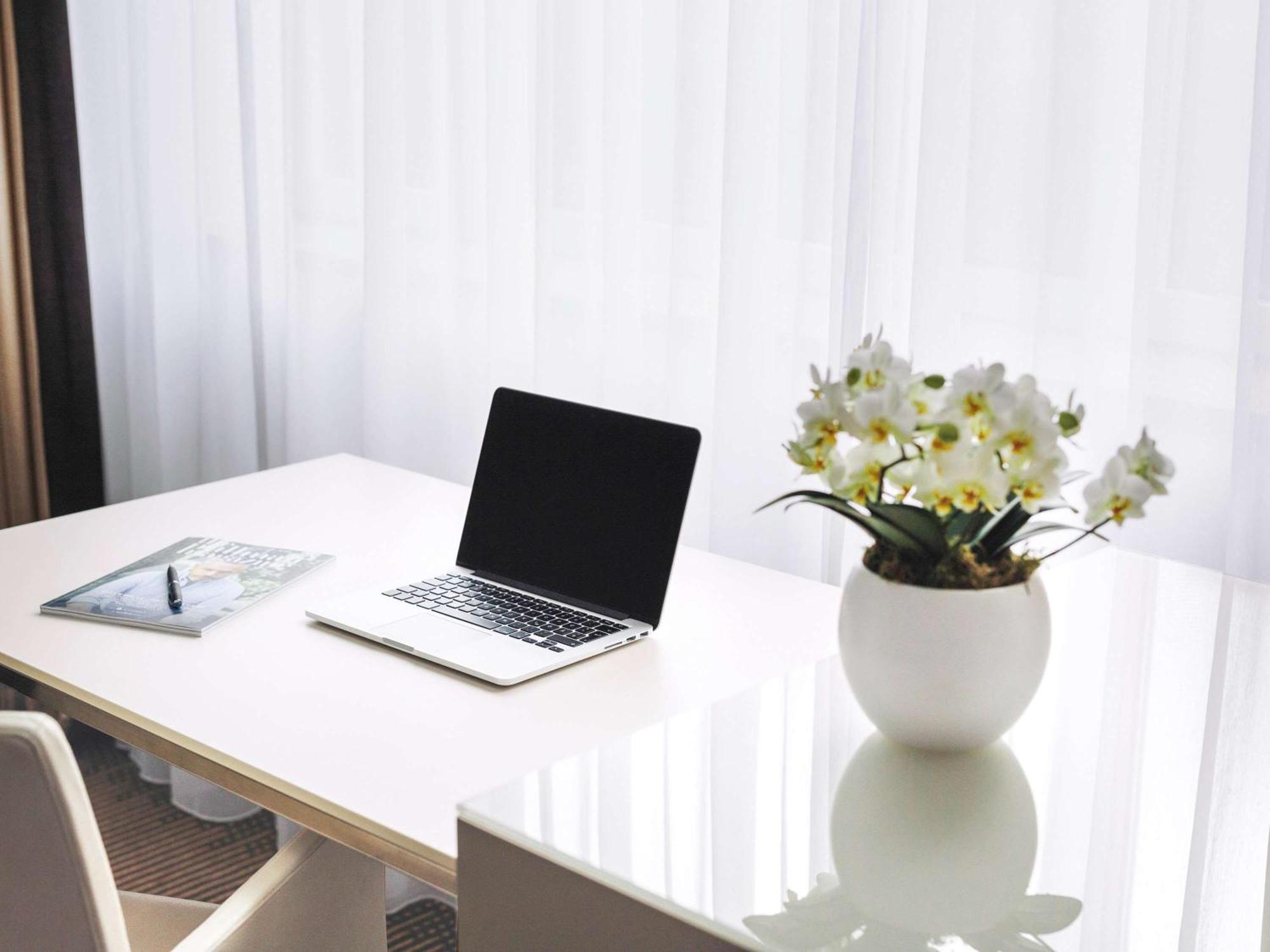 Pullman Berlin Schweizerhof Hotel Luaran gambar A desk with a laptop and a vase of flowers